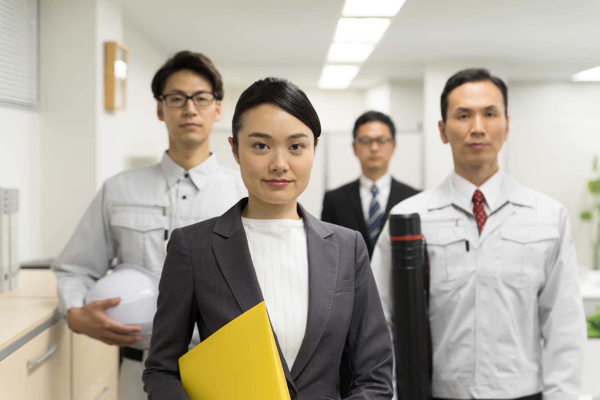 明るい社内できりっと微笑む男女社員
